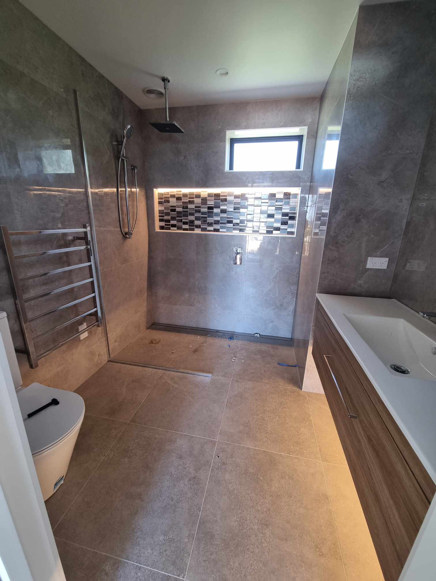 Tiled bathroom with LED-lit mosaic shower niche and heated towel rail