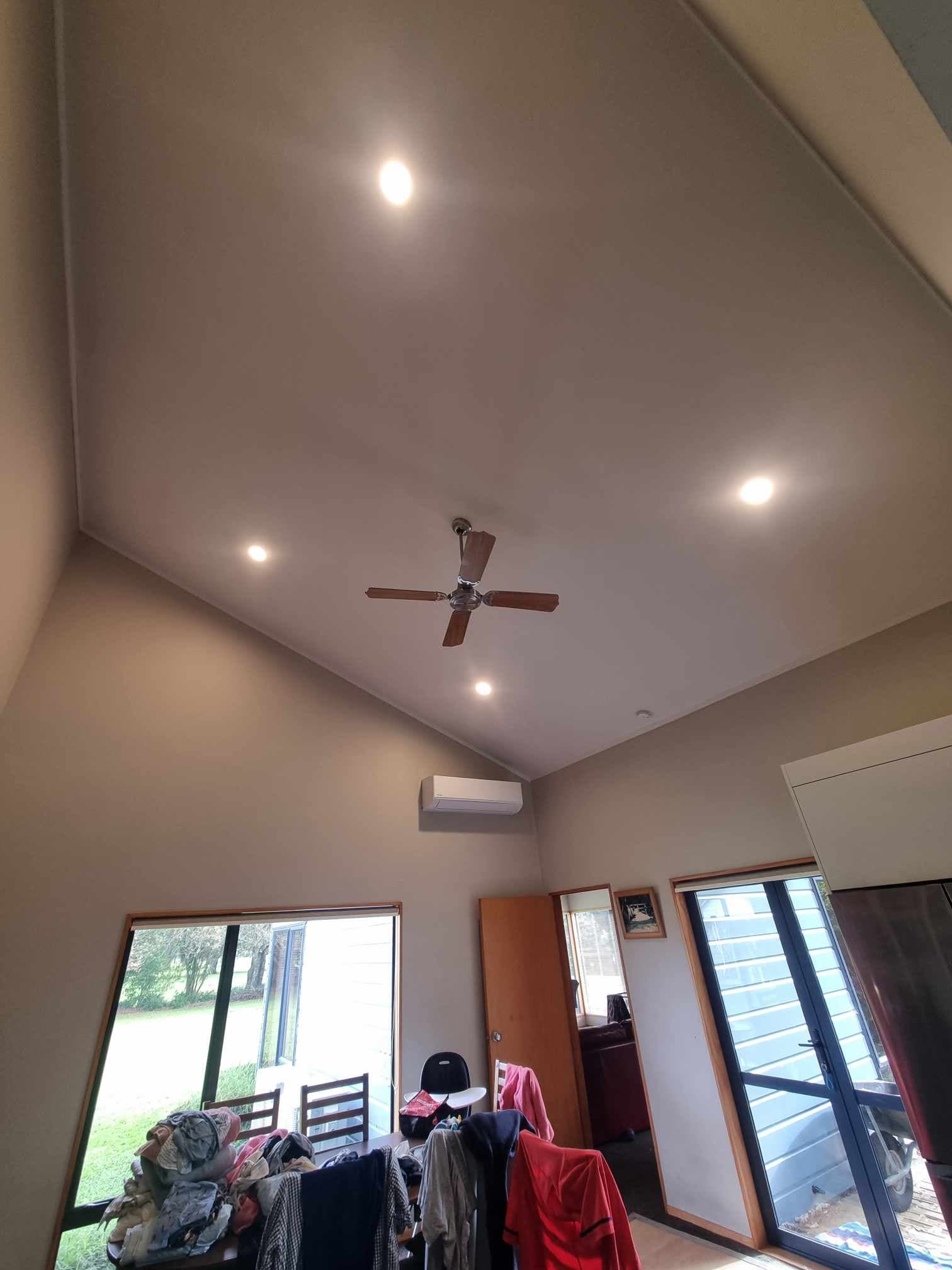 High-wall heat pump and ceiling fan in a raked-ceiling living room