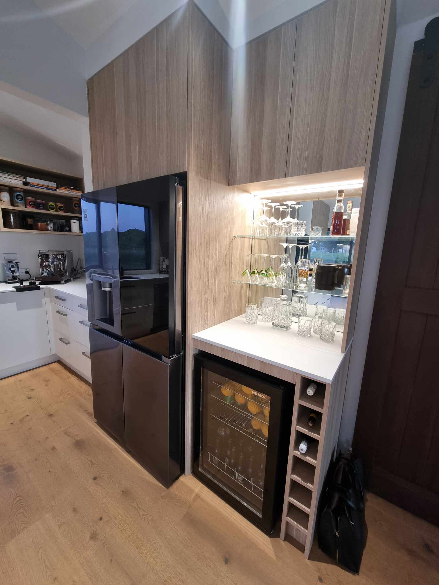 Home bar nook with LED shelf lighting, mirror backing and wine fridge