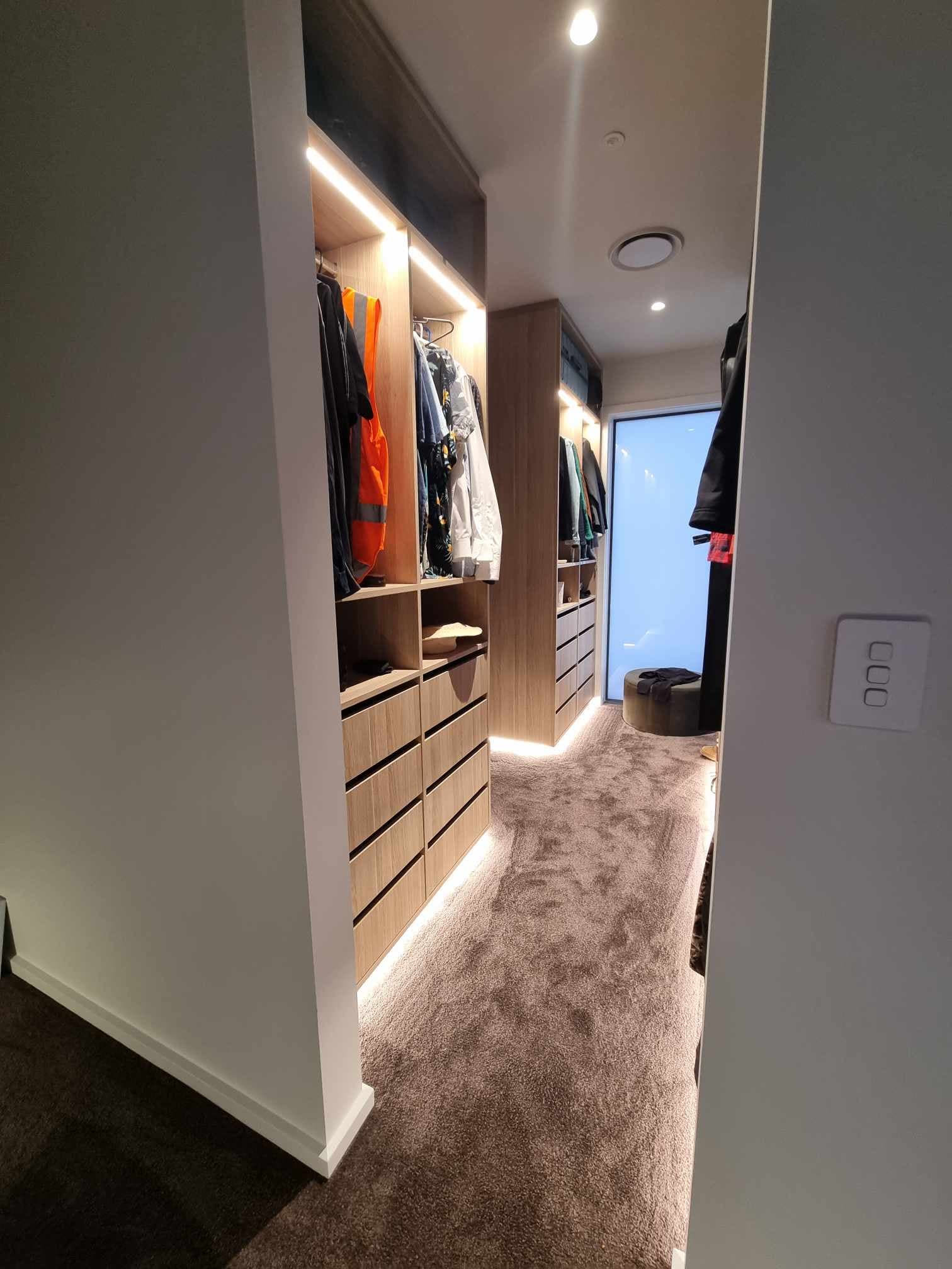 Walk-in wardrobe with LED strip shelf and floor-level lighting