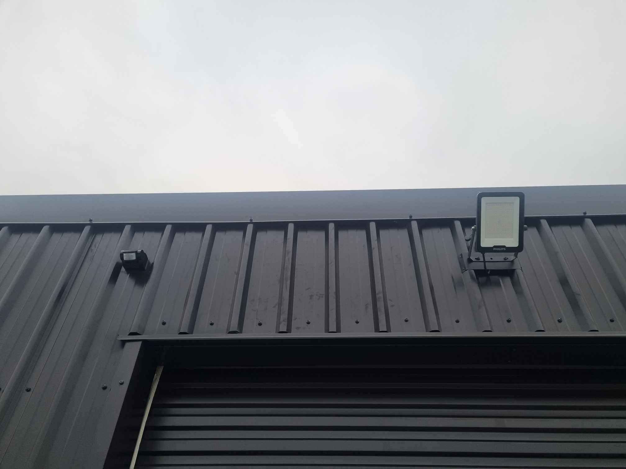 LED security floodlight and motion sensor above a roller door
